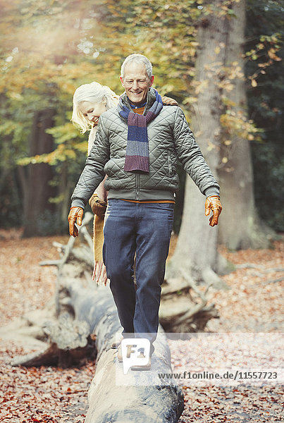 Senior couple walking on log in autumn woods