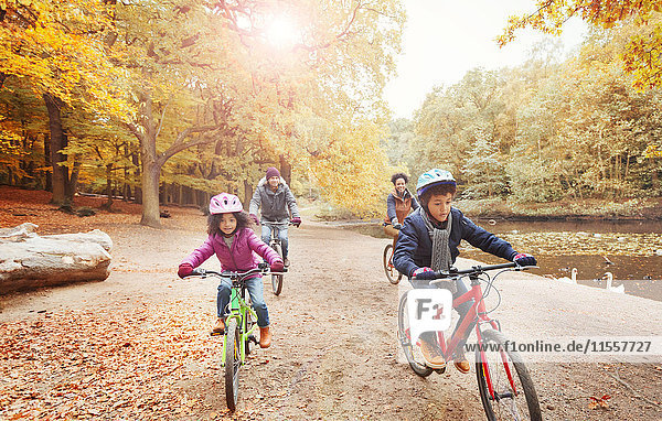 Junges Familienradfahren am Teich im Herbstpark