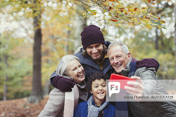 Mehrgenerationen-Familie nimmt Selfie mit Fotohandy im Herbstwald auf