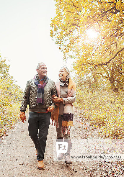 Seniorenpaar mit Arm in Arm auf dem Weg in den Herbstwäldern