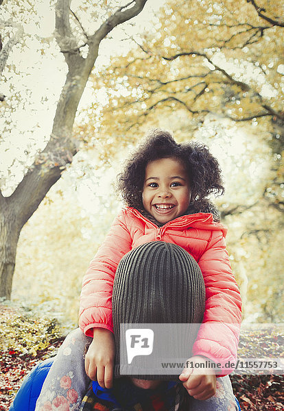 Portrait lächelnde Tochter zieht Strumpfmütze über den Kopf des Vaters im Herbstpark