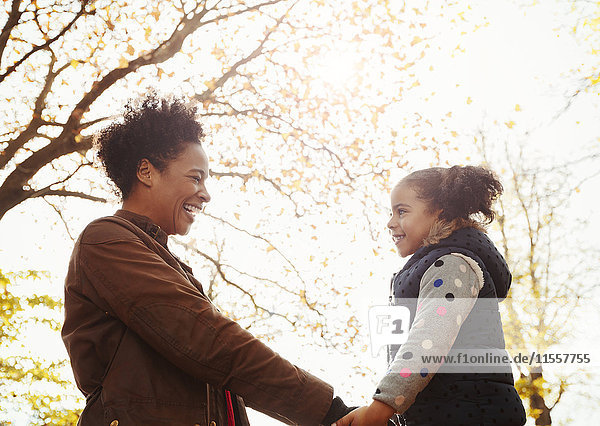 Zärtliche Mutter und Tochter halten Händchen im Herbstpark