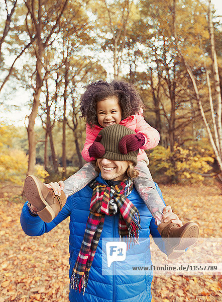 Portrait verspielte Tochter zieht Strumpfmütze über die Augen des Vaters im Herbstpark