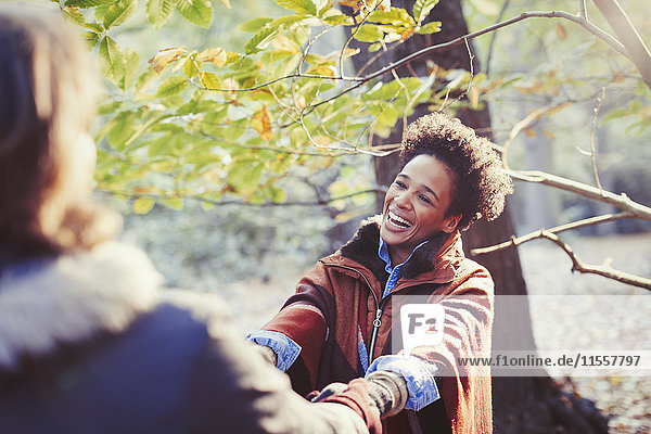 Glückliche Frau hält Händchen mit Freund im sonnigen Herbstpark
