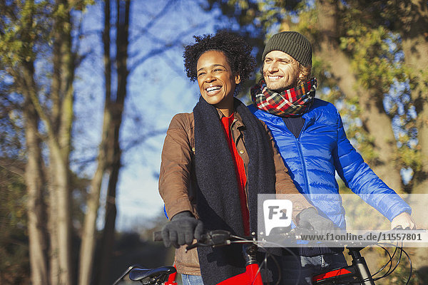 Lächelndes Paar Radfahren im sonnigen Herbstpark