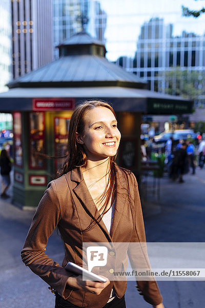 USA  New York  Manhattan  Portrait einer lächelnden jungen Geschäftsfrau mit Tablette