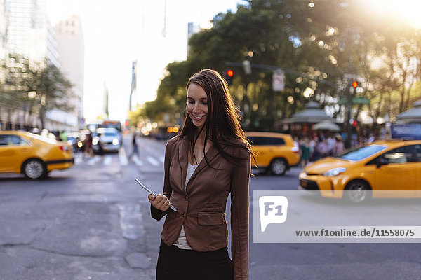 USA  New York  Manhattan  lächelnde junge Geschäftsfrau mit Tablette auf der Straße