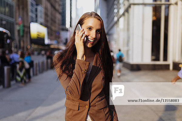 USA  New York  Manhattan  lächelnde junge Geschäftsfrau am Telefon