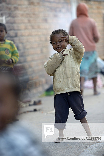 Madagaskar  Fianarantsoa  Obdachloser Junge macht Handzeichen