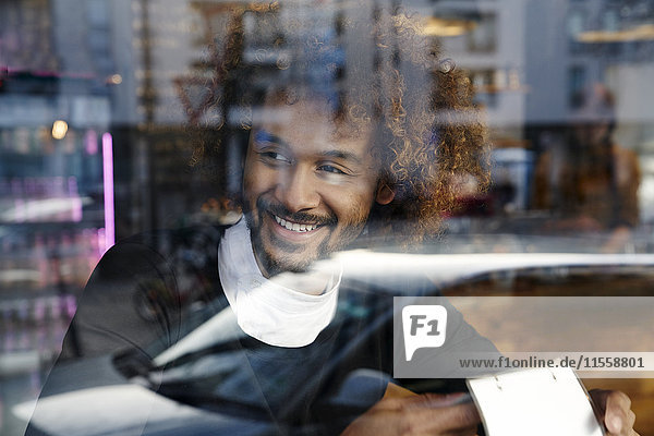 Portrait of smiling young man behind windowpane