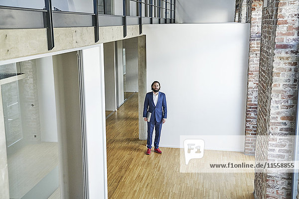 Porträt eines Geschäftsmannes  der auf einer leeren Büroetage steht.