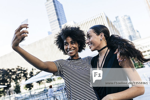 USA  New York City  zwei glückliche junge Frauen nehmen Selfie mit Smartphone