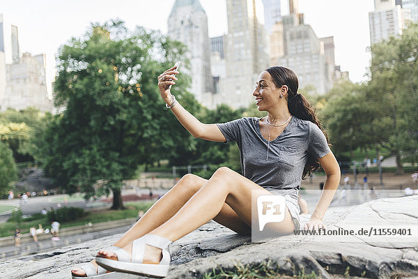 USA  Manhattan  smiling young woman taking selfie with smartphone in Central Park