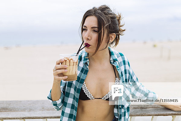 Junge Frau am Strand beim Kaffeetrinken