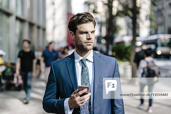 Handsome businessman walking in Manhattan  using mobile phone