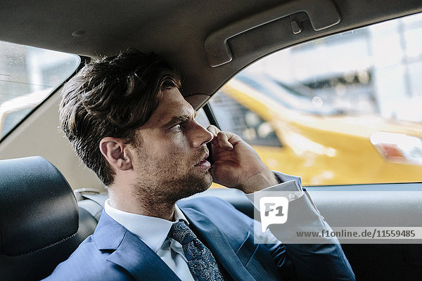 Businessman sitting in taxi  using smart phone