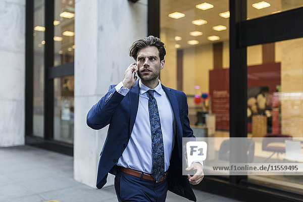Handsone businessman in a hurry running through Manhattan  using smart phone
