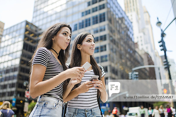 USA  New York City  two twin sisters with cell phones in Manhattan
