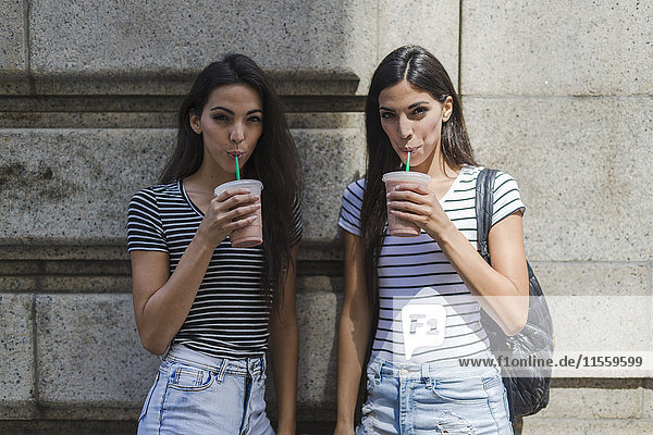 Zwei Zwillingsschwestern bei einem Getränk zum Mitnehmen