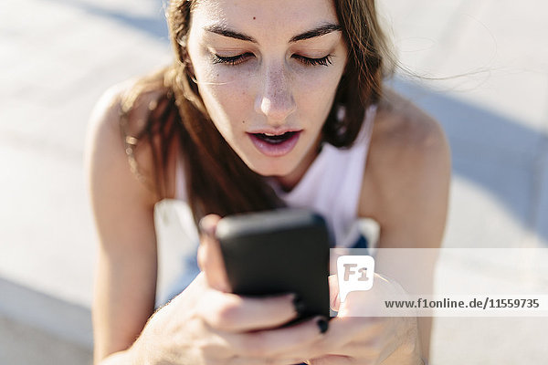Astonished young woman looking at cell phone