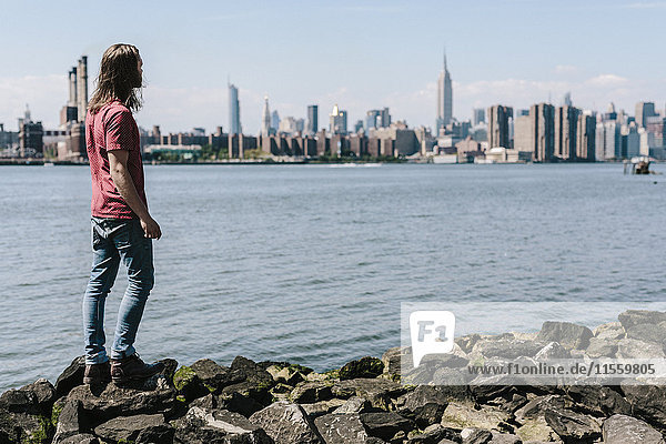 USA  New York City  Mann am Wasser mit der Skyline von Manhattan im Hintergrund