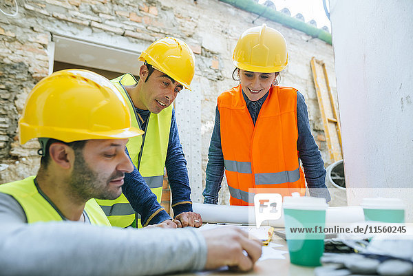 Lächelnde Frau und zwei Bauarbeiter auf der Baustelle