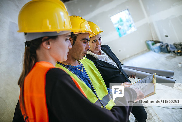 Zwei Frauen und Bauarbeiterinnen auf der Baustelle beim Blick auf den Plan