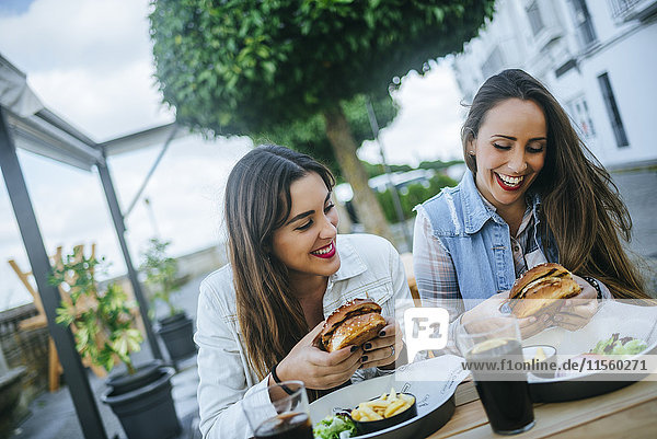 Two women eating Hamburgers in a street restaurant
