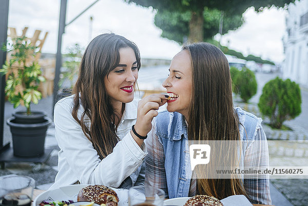 Young woman feeding her friend in a street restaurant