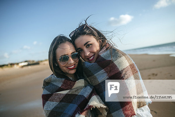 Portrait of two women covered with blanket on the beach