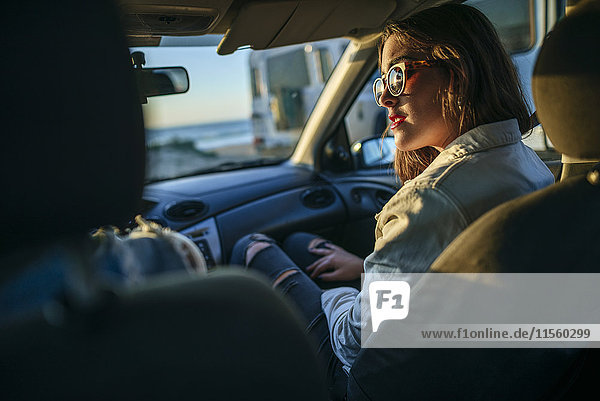 Young woman with sunglasses in car at evening twilight