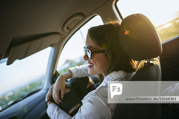 Young woman with sunglasses in car at evening twilight