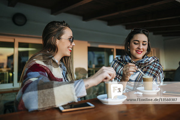 Zwei junge Frauen beim Kaffee im Außencafé