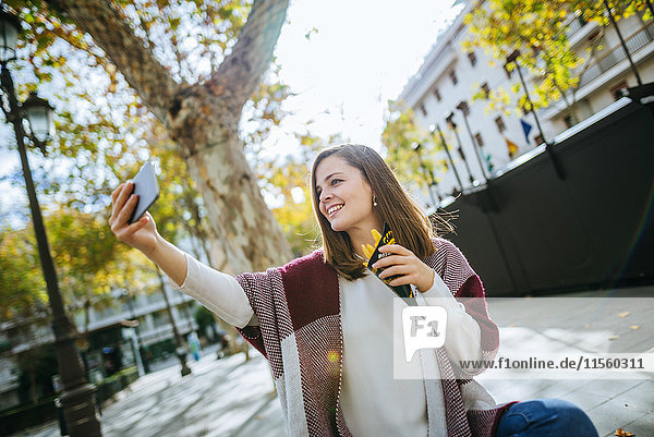 Young woman in Sevilla taking selfie and eating french fries