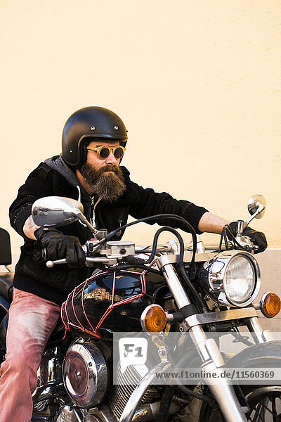 Porträt eines bärtigen Bikers mit Helm und Sonnenbrille auf dem Motorrad