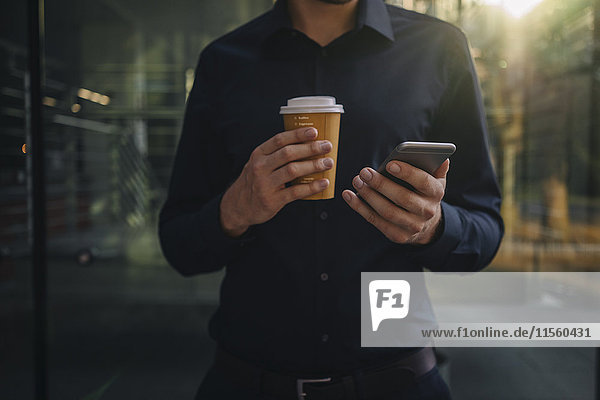 Geschäftsmann mit Kaffee zum Mitnehmen und Smartphone