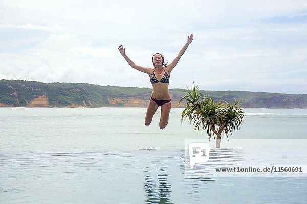 Indonesien  Insel Lombok  Frau springt in den unendlichen Pool