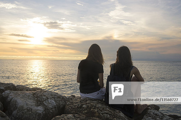 Indonesia  Bali  two women watching the sunset over the ocean