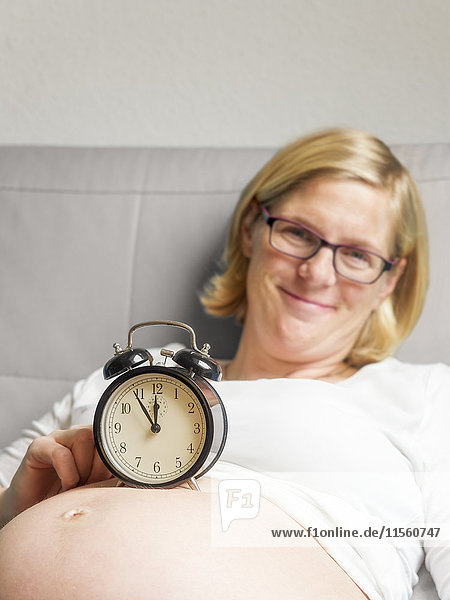 Pregnant woman with alarm clock on her belly