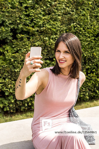Portrait of smiling young woman taking selfie with cell phone