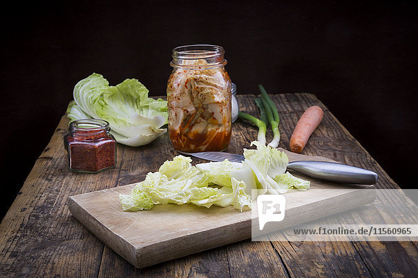 Glas Kimchi und Zutaten auf dunklem Holz