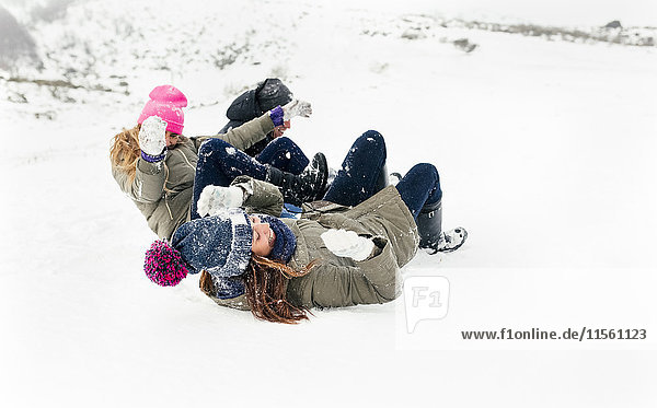 Drei Freunde  die auf dem Schnee rutschen