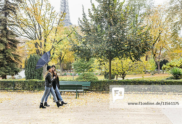 France  Paris  two young women walking in park with the Eiffel Tower in the background