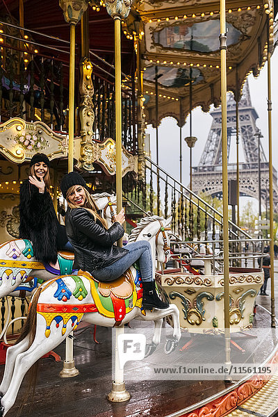 Frankreich,  Paris,  zwei beste Freunde beim Karussellfahren mit dem Eiffelturm im Hintergrund