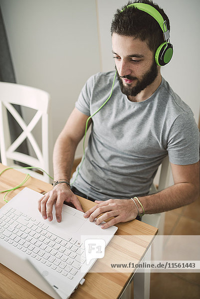 Young man wearing headphones  using laptop