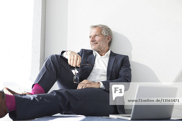 Businessman sitting on the floor next to laptop