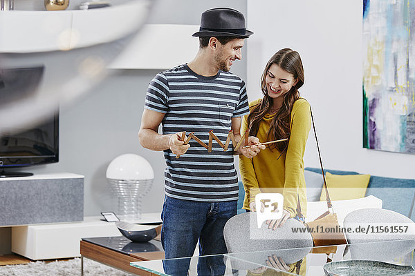 Couple in furniture store measuring dining table with pocket rule