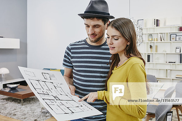 Couple with floor plan choosing furniture in furniture shop