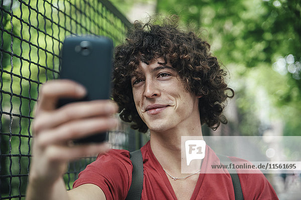 Junger Mann nimmt einen Selfie mit Smartphone