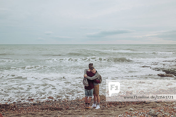 Schwules Paar  das sich am Strand vor dem Meer umarmt